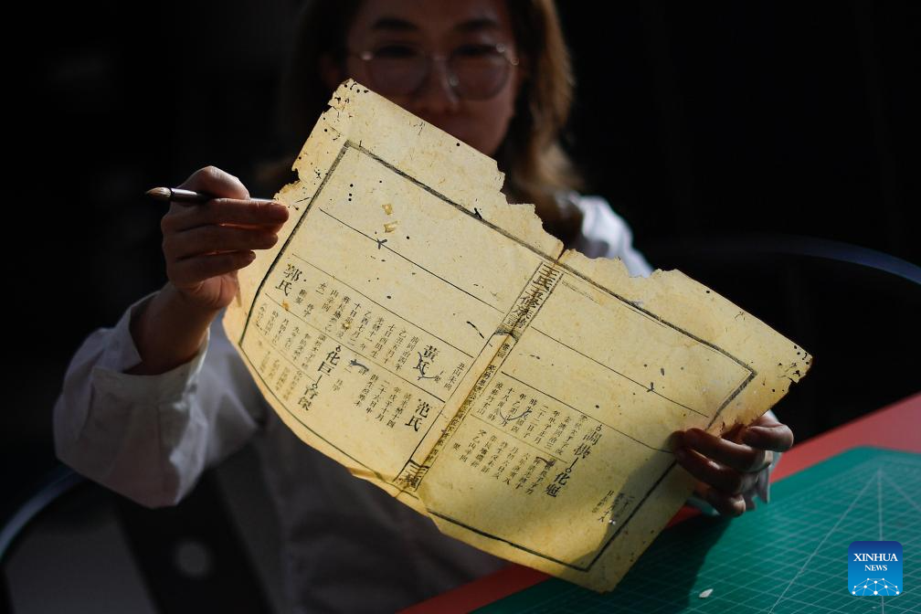 Η Τζανγκ Χουά, μια συντηρήτρια αρχαίων βιβλίων στη βιβλιοθήκη του ΠανεπιστημίουΤζιλίν, παρατηρεί την ζημιά σε ένα βιβλίο για συντήρηση, στο Τσανγκτσούν, βορειοανατολική επαρχία Τζιλίν της Κίνας, 19 Απριλίου 2024.