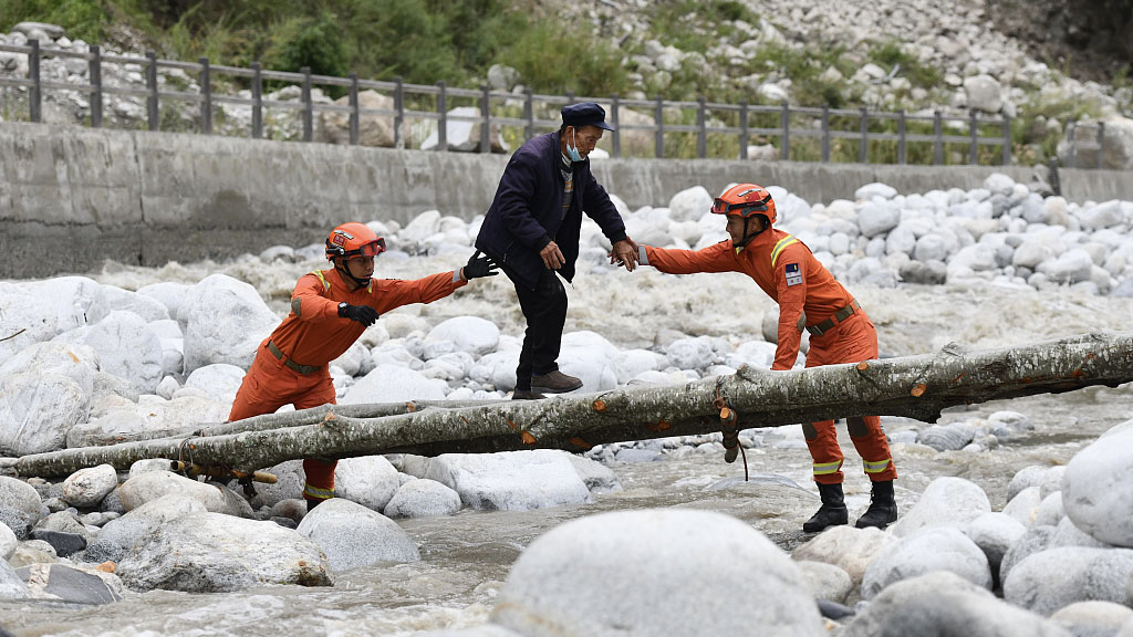 Zjarrfikësit ndihmojnë një burrë të kalojë një urë të përkohshme në Luding County, Provinca Sichuan e Kinës jugperëndimore, 6 shtator 2022