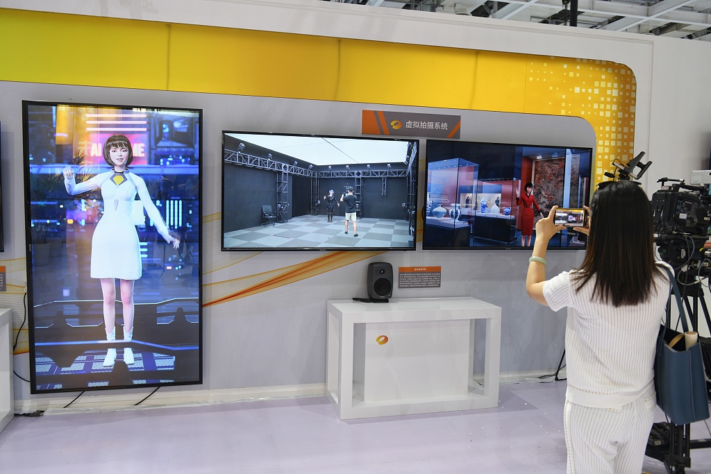 O altă femeie pasionată de tehnologie fotografiază un personaj virtual de pe ecran.