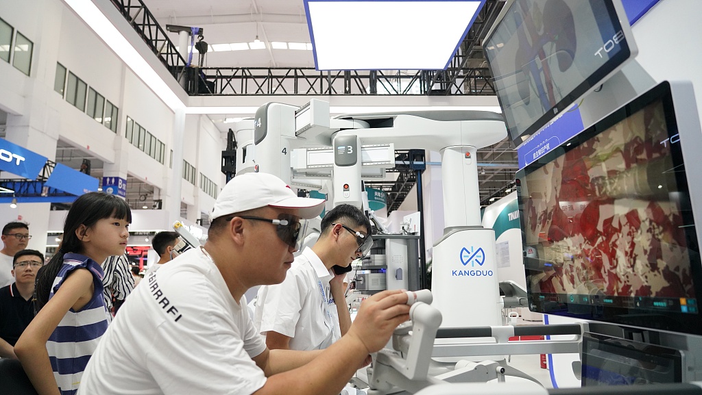 Un vizitator privește un robot făcând o operație