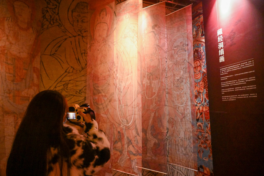 Επισκέπτης παρατηρεί εκθέματα σε μια έκθεση με θέμα τον πολιτισμό του Ντουνχουάνγκ στο Μουσείο Ψηφιακής Τέχνης στο Τιεντζίν στη βόρεια Κίνα, 28 Νοεμβρίου 2023. Η έκθεση θα διαρκέσει μέχρι τον Μάρτιο του 2024. [Φωτογραφία/Xinhua]