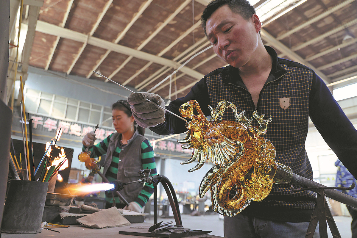 Τεχνίτες στο Εργαστήριο Σιγιέ δημιουργούν κομμάτια τέχνης από γυαλί σε σχήμα δράκου στις 23 Ιανουαρίου. [Φωτογραφία Wang Jing/China Daily]