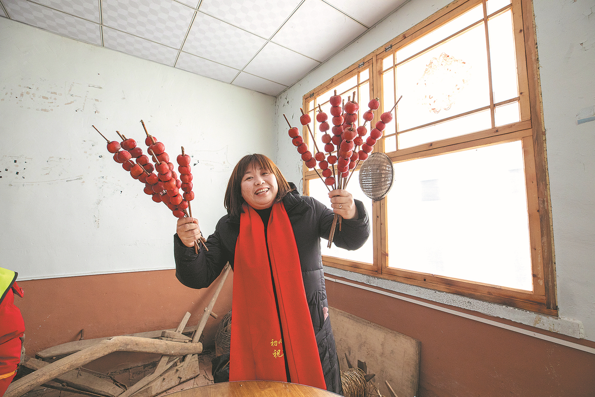 Η Τζανγκ Ντονγκ κρατάει ένα καλυμμένο με ζάχαρη τσάι σε ξυλάκια που έχουν ετοιμαστεί για τους μαθητές της στην πόλη Τζιλίν της επαρχίας Τζιλίν. [Φωτογραφία για την CHINA DAILY]