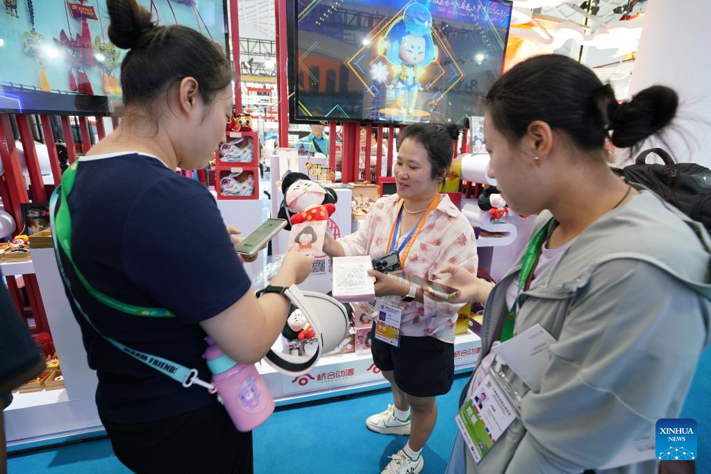 Εκθέτης (κέντρο) παρουσιάζει στους επισκέπτες μια κούκλα εμπνευσμένη από μια γυναικεία φιγούρα της δυναστείας Τανγκ (618-907) στην τέταρτη Διεθνή Έκθεση Καταναλωτικών Προϊόντων της Κίνας (CICPE) στο Χαϊκόου, πρωτεύουσα της επαρχίας Χαϊνάν της νότιας Κίνας, 14 Απριλίου 2024. (Xinhua/Li Mengjiao)